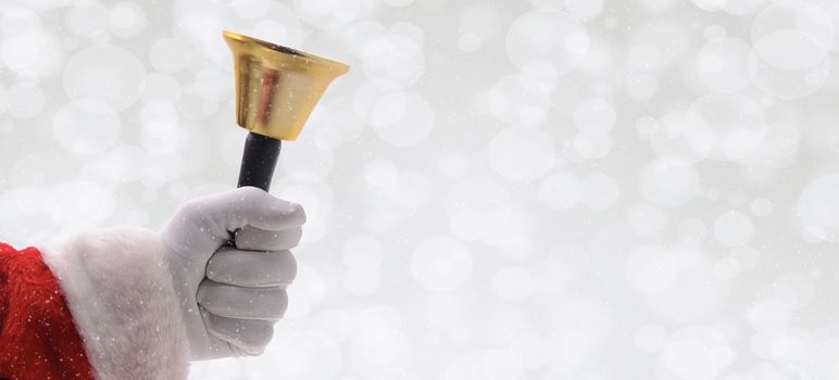 Closeup of Santa Ringing a gold bell over a silver bokeh background with snow effect.