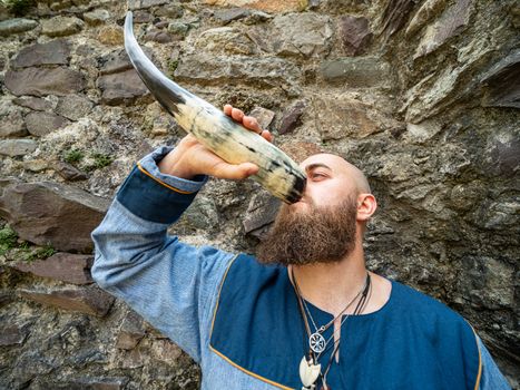 Portrait of a young warrior drinking from a Viking horn, outdoor setting