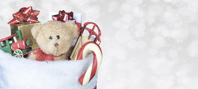 Christmas Stocking filled with toys - Banner size copy space. Bokeh Background with snow effect.