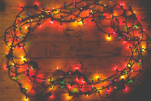 Christmas rustic background - vintage planked wood with lights and copy space. Garland. Tinted photo. Flat lay, top view. 