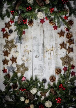 Christmas decoration composition. Frame made of fir branches, pinecones and berries on the wooden board in vintage style. Flat lay, top view, copy space. 