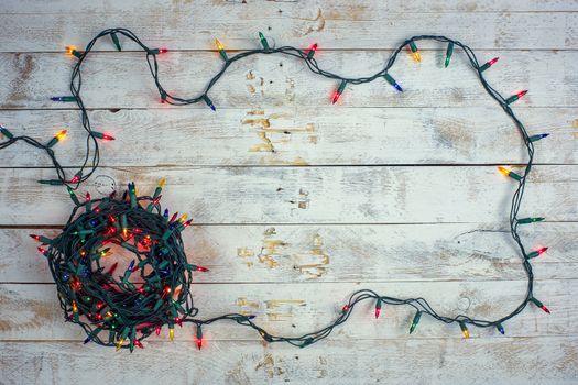 Christmas background with colorful lights and free text space. Garland lights frame on a wooden background. Flat lay, top view, copy space. 