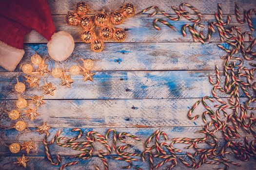 Christmas background with santa hat and christmas lights with candy canes on rustic, vintage blue and white wooden background. Flat lay, top view, copy space. 
