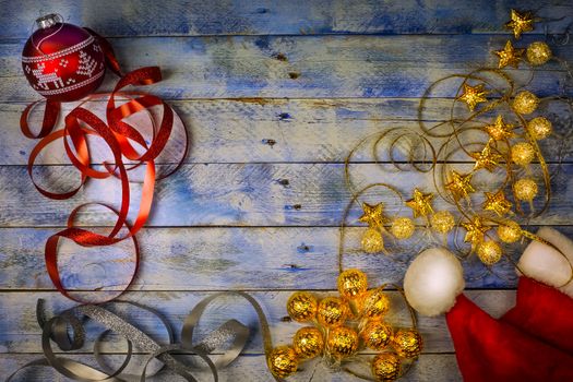 Christmas background. Top view of Christmas red ball, santa hat and christmas lights with ribbons on rustic vintage wooden background. Flat lay, copy space. 