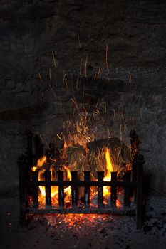 Old fashioned open log fireplace in with flames and sparks