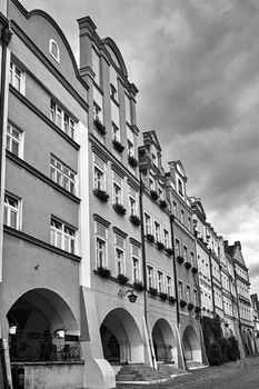Facades of historic tenement houses with arcades on the market in the city of Jelenia Gora in Poland, black and white