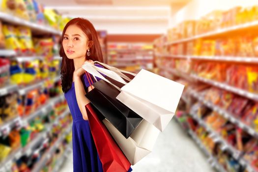 Happy women in blue dress with a shopping bag in shopping mall