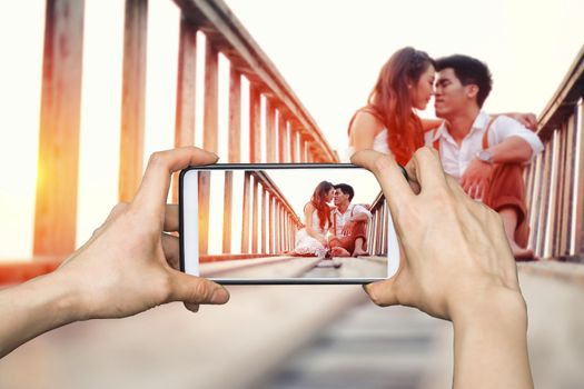 Girl taking pictures on mobile smart phone Happy couple relaxing in sunset 