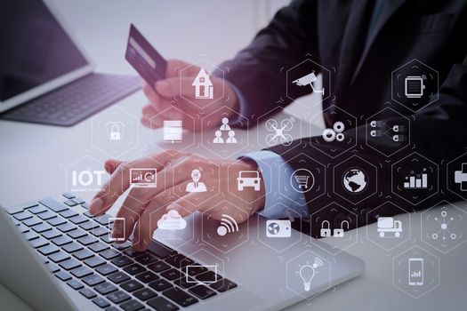 Internet of Things (IOT) technology with AR (Augmented Reality) on VR dashboard. businessman making credit card purchase online with laptop computer on modern desk 