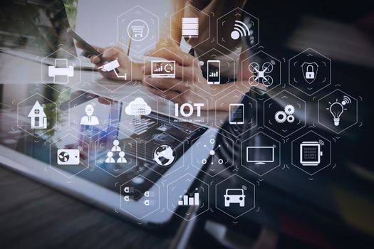 Internet of Things (IOT) technology with AR (Augmented Reality) on VR dashboard. designer hand working with digital tablet and laptop computer and book stack  on wooden desk as concept