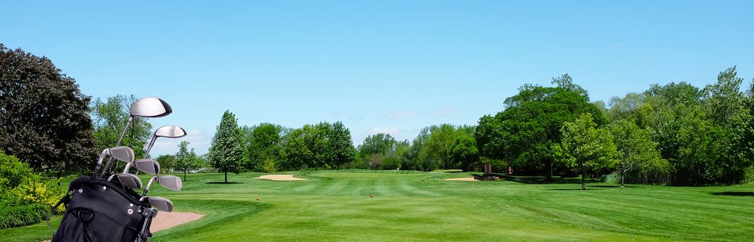 Golf Banner: A Golf bag with clubs on a par three tee box. Blue Sky and room for copy.