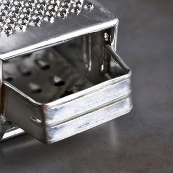 Closeup of a metal cheese grater on a baking sheet.