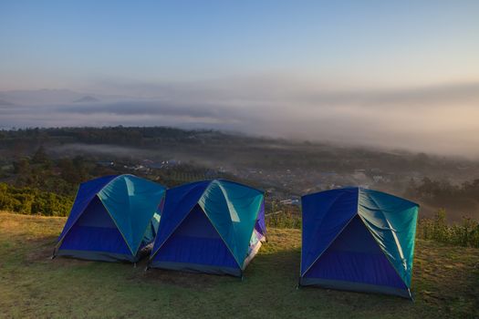 Camping tent on green grass field on mountain under clear sky located at north of Thailand