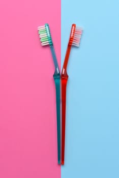 Two toothbrushes on a pink and blue background. Flay lay high angle view with copy space.