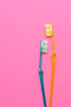 Two toothbrushes on a pink and blue background. Flay lay high angle view with copy space.