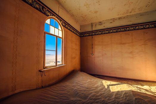 Empty room with a window and desert sand located in the ruins of the ghost town Kolmanskop in the Namib desert near Luderitz, Namibia, Southern Africa