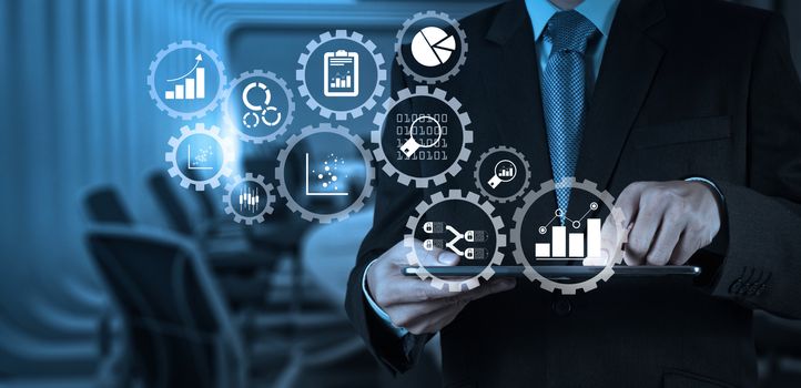 Business data analytics management with connected gear cogs with KPI financial charts and graph.Businessman hand working with a digital tablet on meeting room background