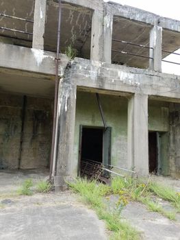 old abandoned grey cement building with weeds growing