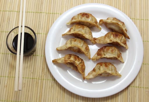 Asian Fried Dumplings with soy sauce and chopsticks on bamboo placemat