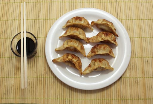 Asian Fried Dumplings with soy sauce and chopsticks on bamboo placemat