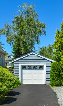 Stand along single garage on a back yard with asphalt driveway