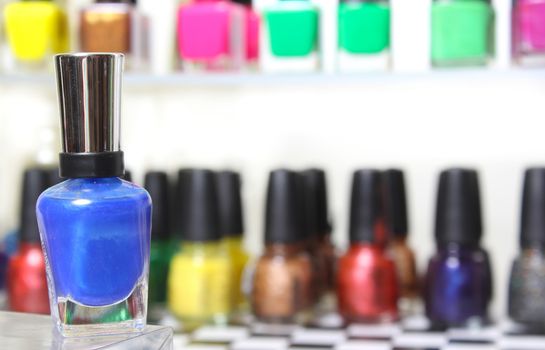 Blue Nail Polish With Blurred Nail Polish Display in Background