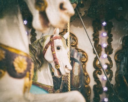 Vintage carousel white horses, retro look with old film color palette and scratches