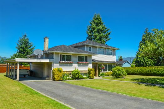 North American family house with big front yard and blue sky background. Family house with asphalt driveway and parking under the roof