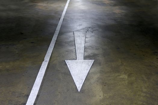 white arrow symbol sign on cement floor walkway parking