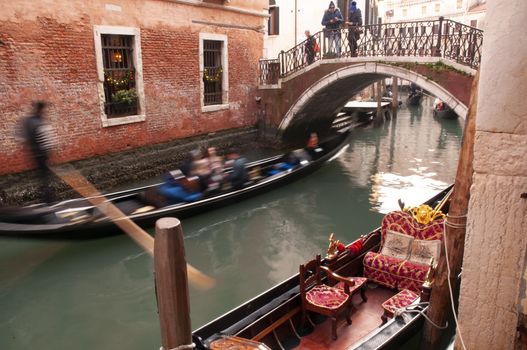 Blurred gondola with scared tourists cross one of the most stone bridges in Venice