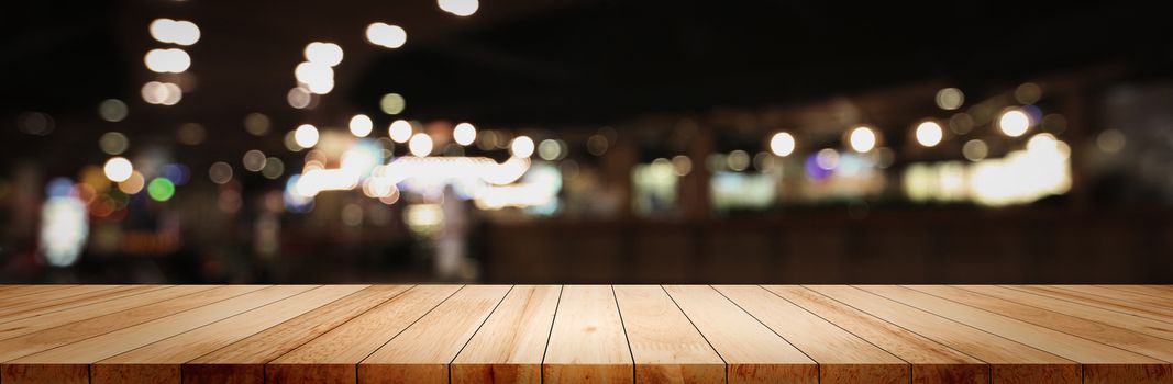 Panoramic empty clean wood counter table top on blur street night cafe background use for pub coffee shop montage dark scene, Blurry wide wooden texture shelf bar in luxury restaurant kitchen backdrop