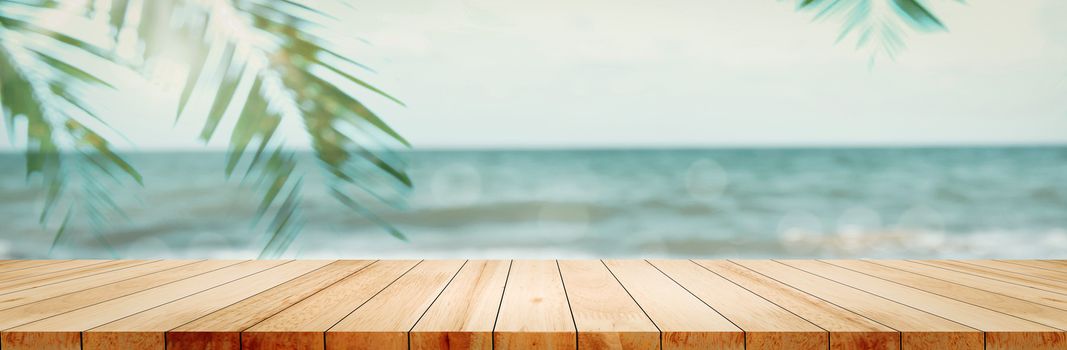Panoramic empty clean wood counter table top blur shinny white bokeh light on summer beach background for product morning scene display montage, Abstract Blurry wooden desk in vacation trip backdrop.