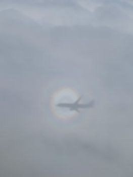 shadow of the airplane on the cloud with the rainbow circle