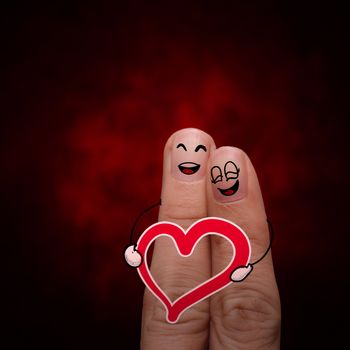 A happy finger couple in love with painted smiley and hold heart