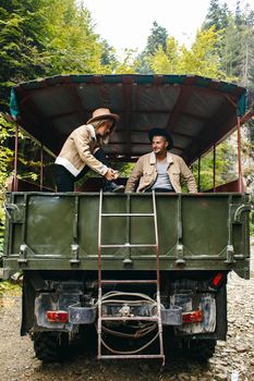 A beautiful girl and a handsome man in military truck. Lovestory. Military vehicle. Military fashion.Carpathian mountains.