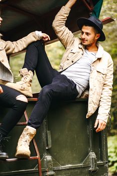 A beautiful girl and a handsome man in military truck. Lovestory. Military vehicle. Military fashion.Carpathian mountains.