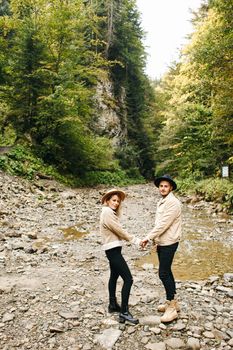 Young couple at the Carpathian - Happy tourists visiting mountains. Lovestory. Tourists in hats. Military fashion