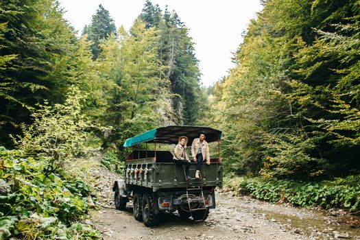 A beautiful girl and a handsome man in military truck. Lovestory. Military vehicle. Military fashion.Carpathian mountains.