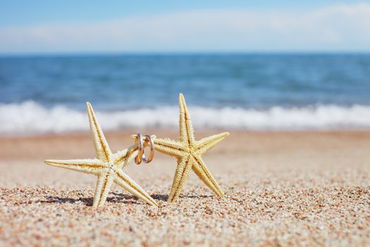 Starfish with wedding rings on the beach. Summer vacation concept. Family holidays by the sea. High quality photo