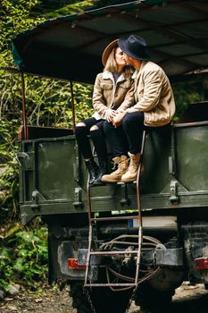 A beautiful girl and a handsome man in military truck. Lovestory. Military vehicle. Military fashion.Carpathian mountains.