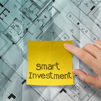 hand point smart investment sticky note with crumpled blue print part of architectural project