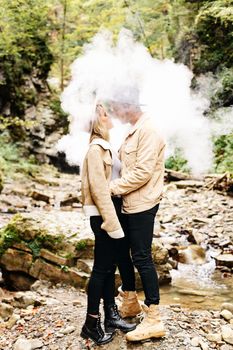 Couple in vape cloud. Two in smoke. Tourists in cold autumn forest with vape. Man and women in smoke. Two smokers. Beautiful couple in fog. E-cigarettes and people