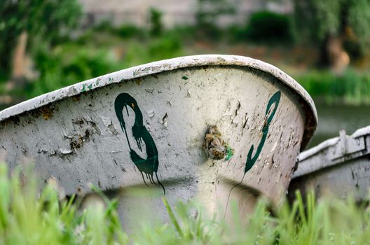 old boat number three on the river bank on green grass without people