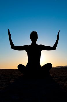 Silhouette of woman in yoga lotus meditation position with arms up