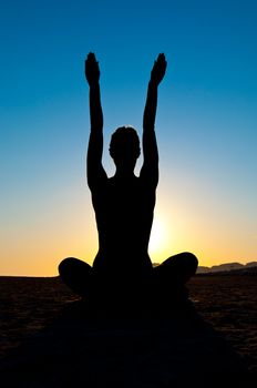 Silhouette of woman in yoga lotus meditation position with arms up