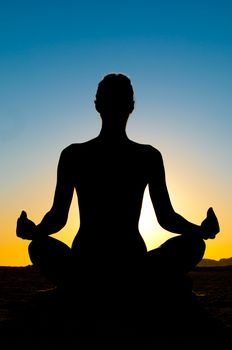 Silhouette of woman in yoga lotus meditation position