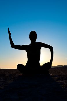Silhouette of woman in yoga meditation position with arms up