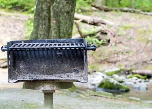 Horizontal close-up shot of a well used public area barbecue grill straight on. 