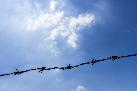 Silhouetted of a single barbed wire against an amazing bright sky.