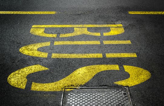 Yellow bus traffic sign painted on asphalt road.